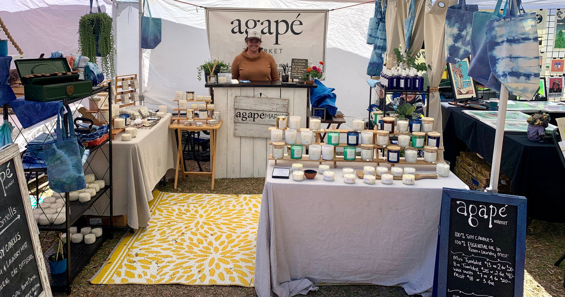 Katie Borland in a pop up market tent with handmade products on tables and shelves.