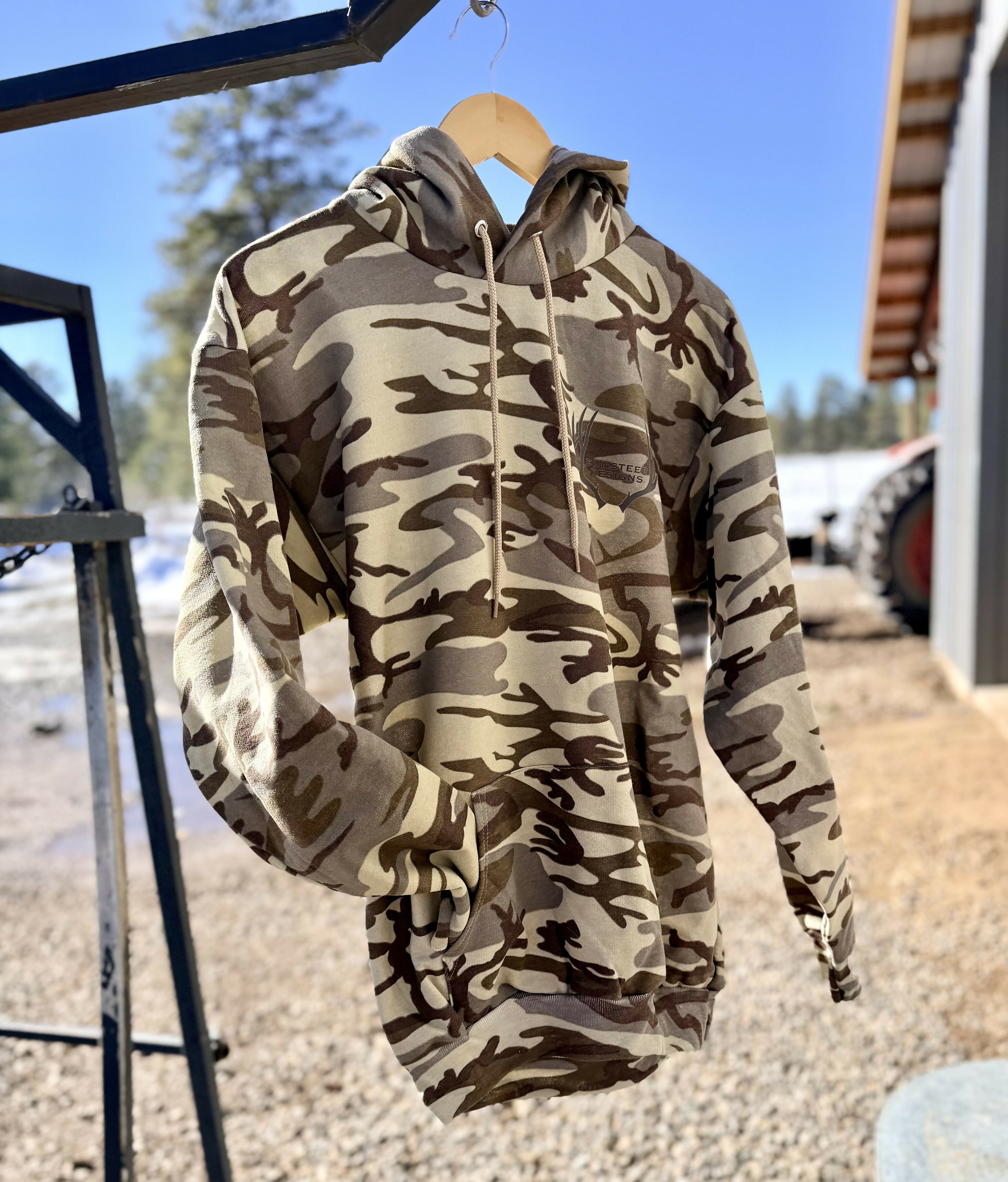 camo hoodie hanging on a steer chute, outside with a blurred background