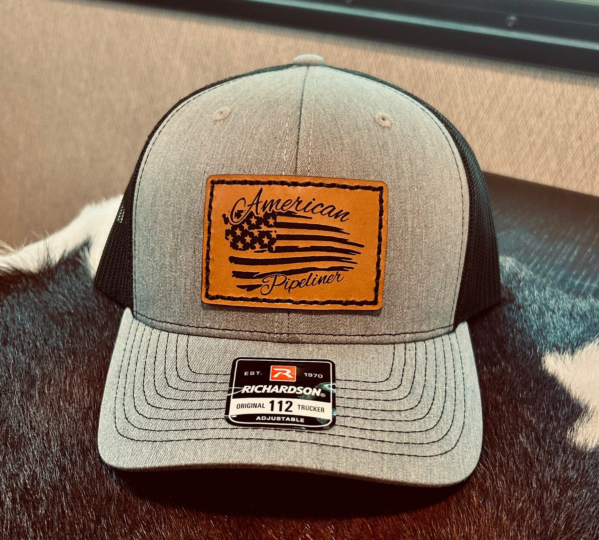 Gray cap with leather patch and Richardson logo on a textured surface