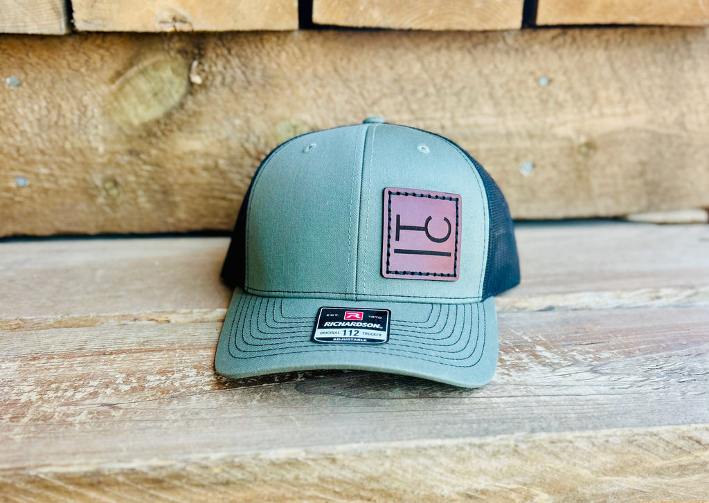 Green and black cap with a logo on a leather patch on a wooden surface