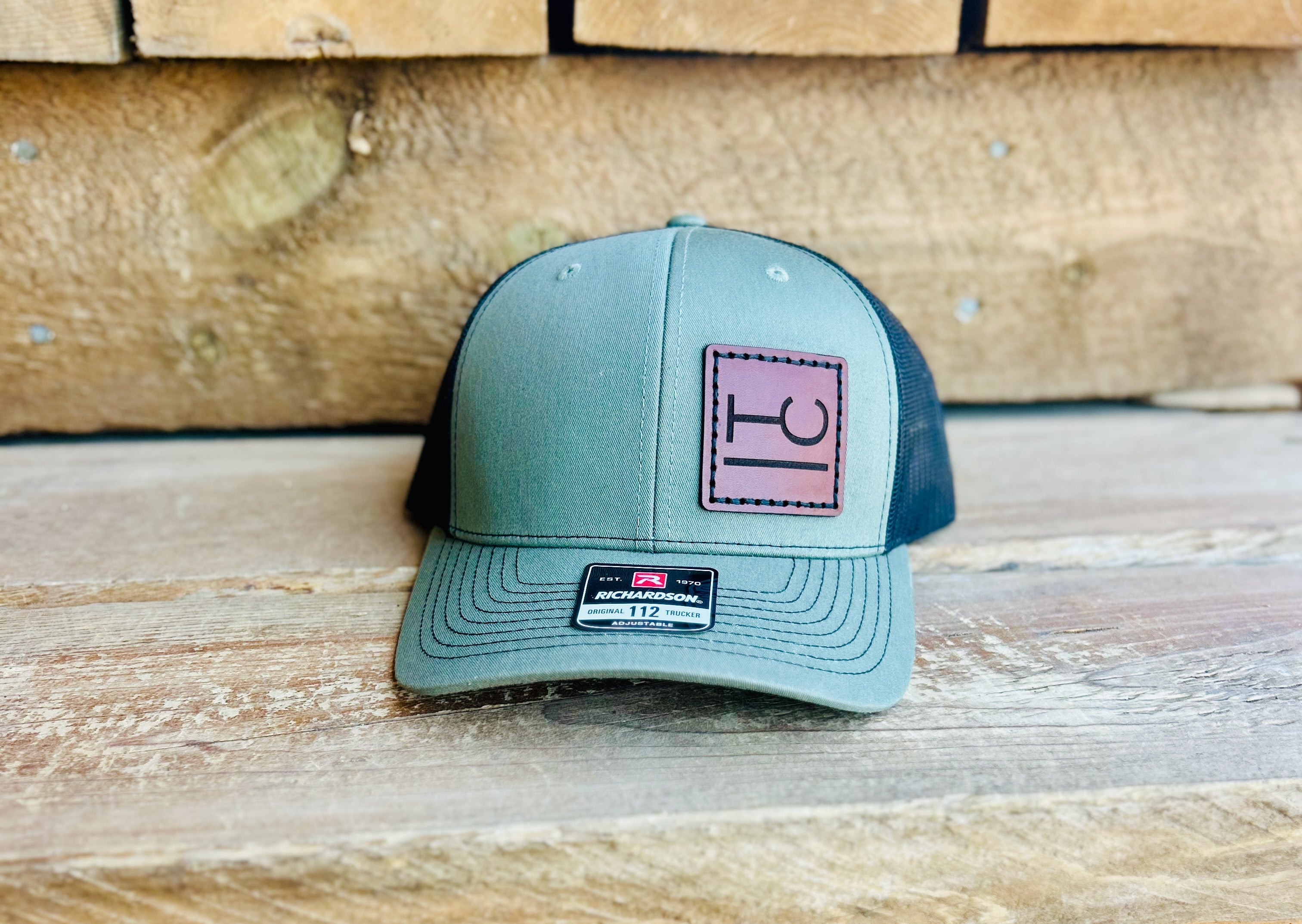 Green and black cap with a logo on a leather patch on a wooden surface