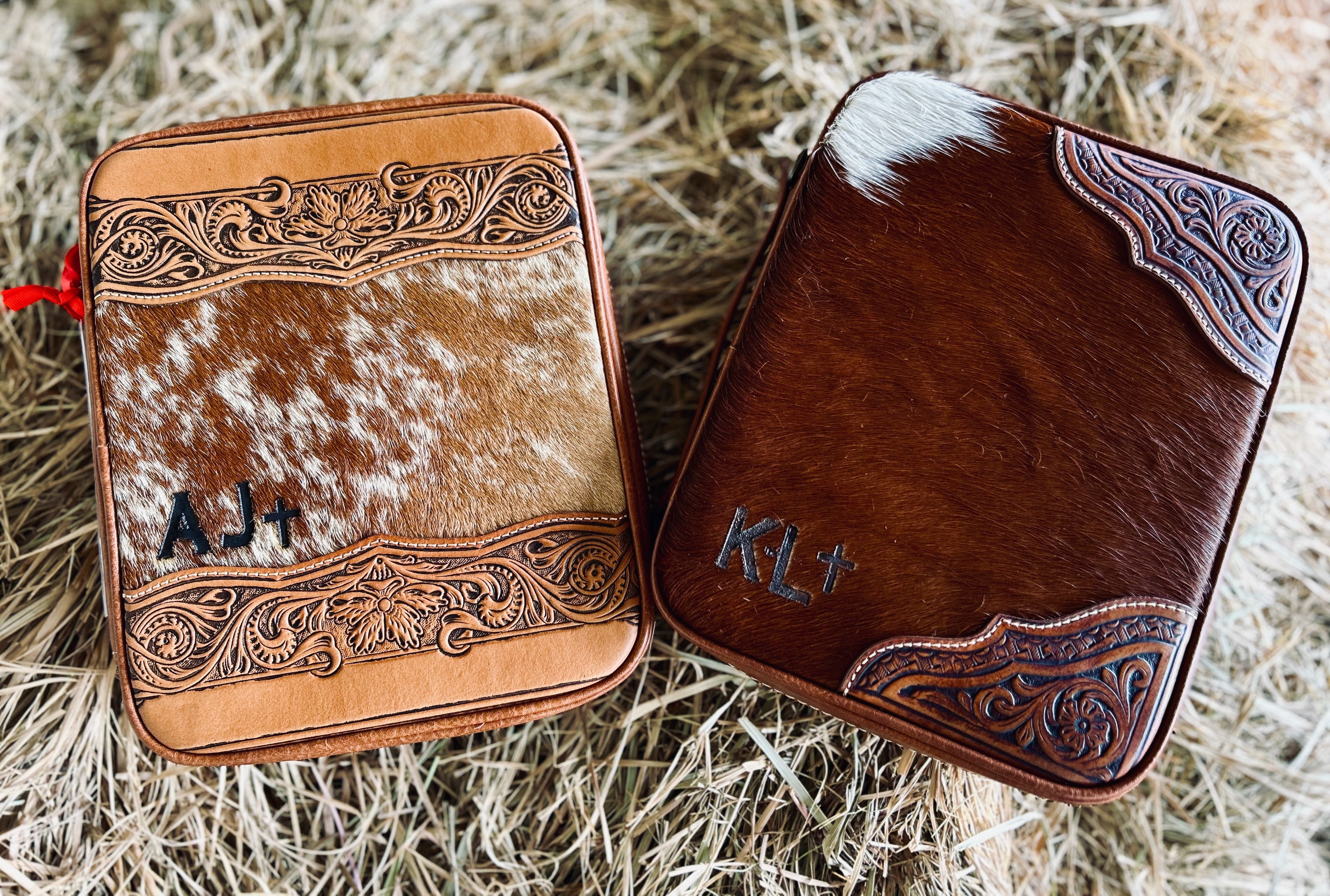 Two leather cases with decorative patterns and initials on a hay background
