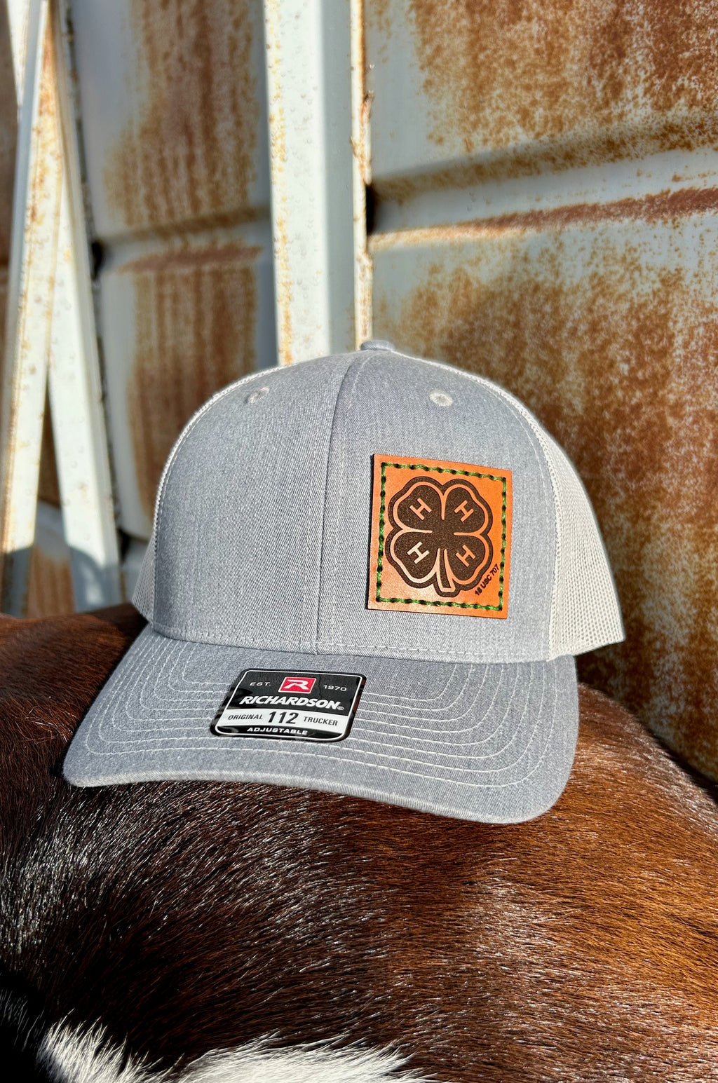 Gray cap with a leather patch on a horse's back against a rusty metal background