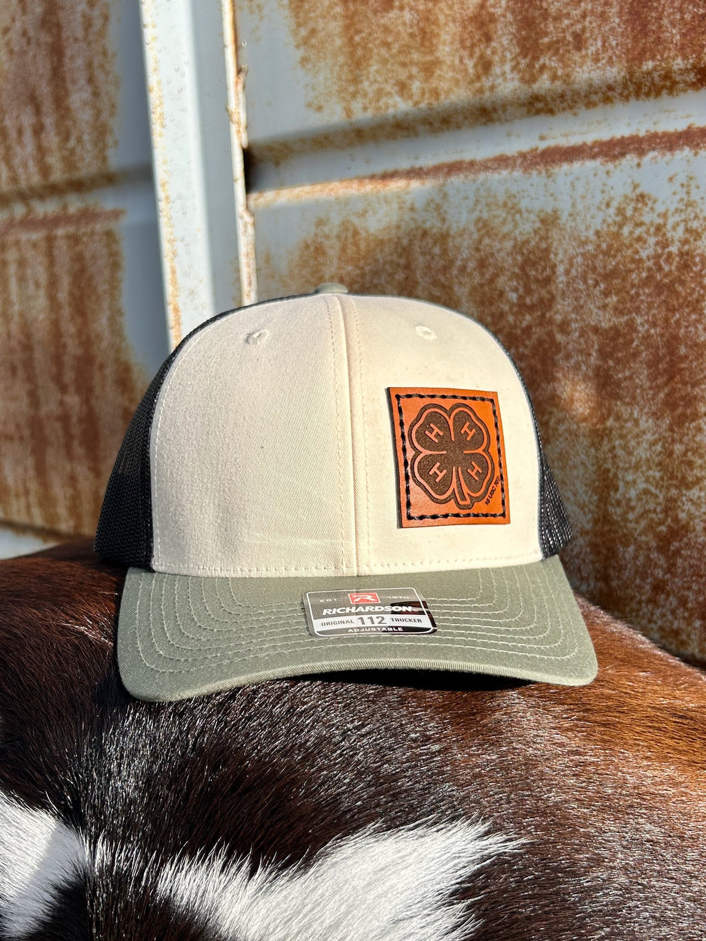 Beige and green cap with leather patch on a cow's back