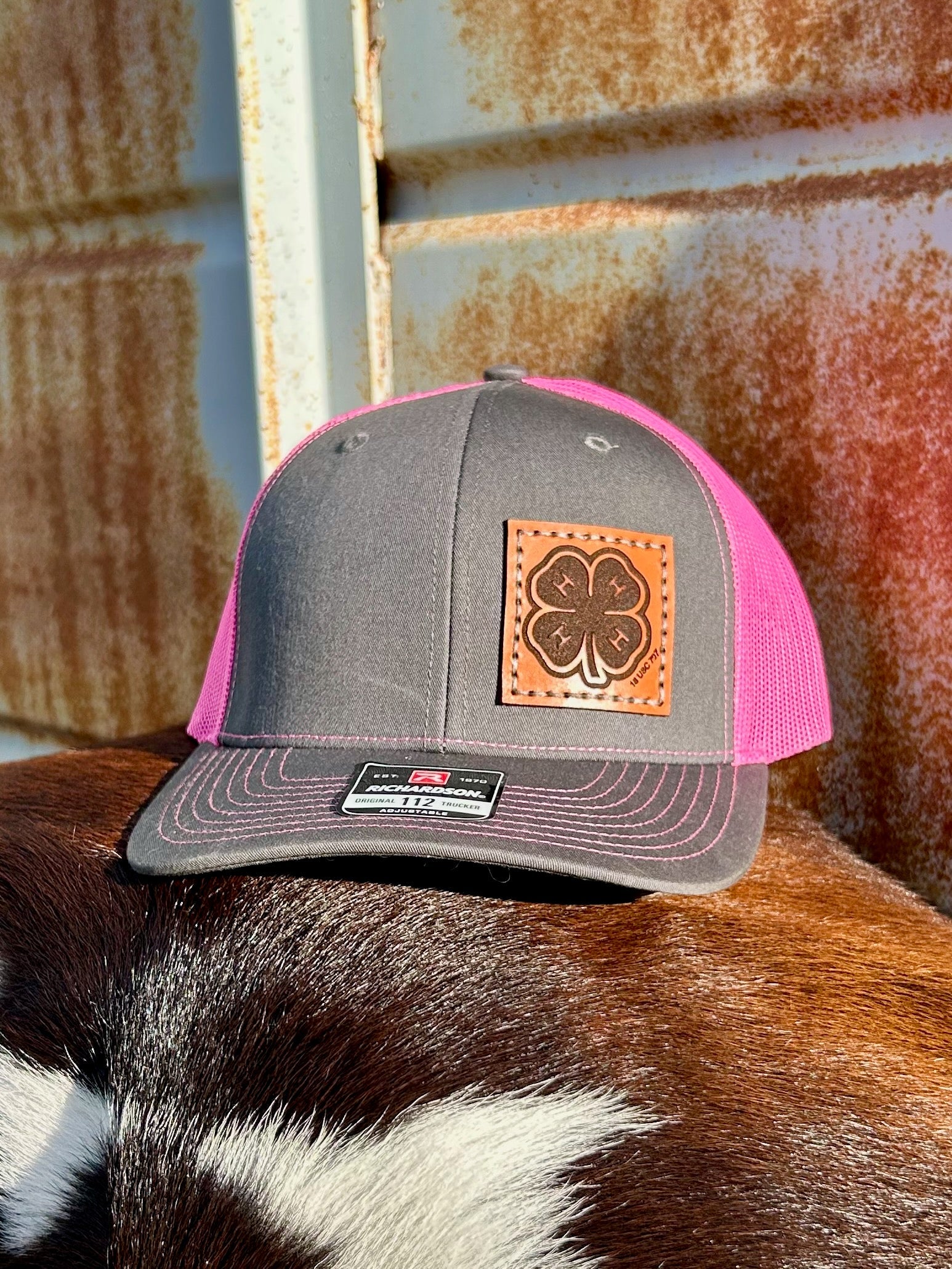 Gray and pink cap with a leather patch featuring a four-leaf clover on a cow.