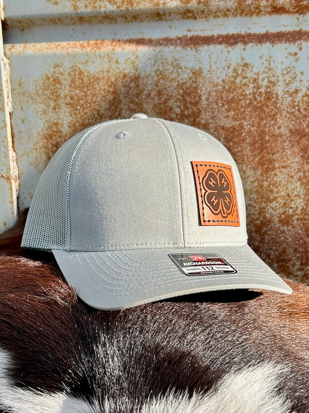Gray cap with a leather patch on a horse's back against a rusty metal background