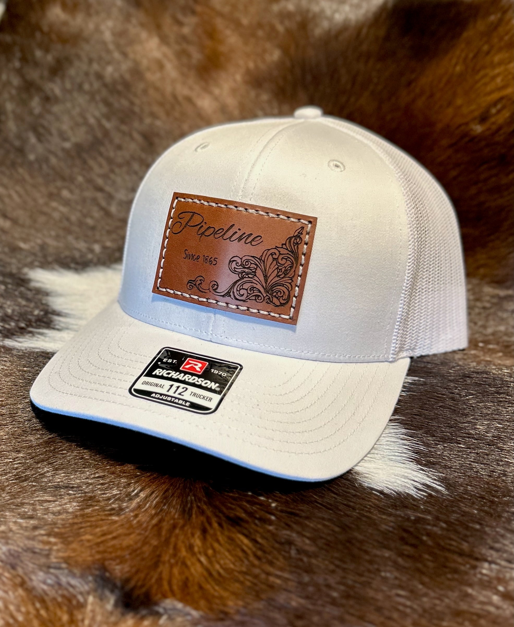 White cap with brown leather patch on a fur background