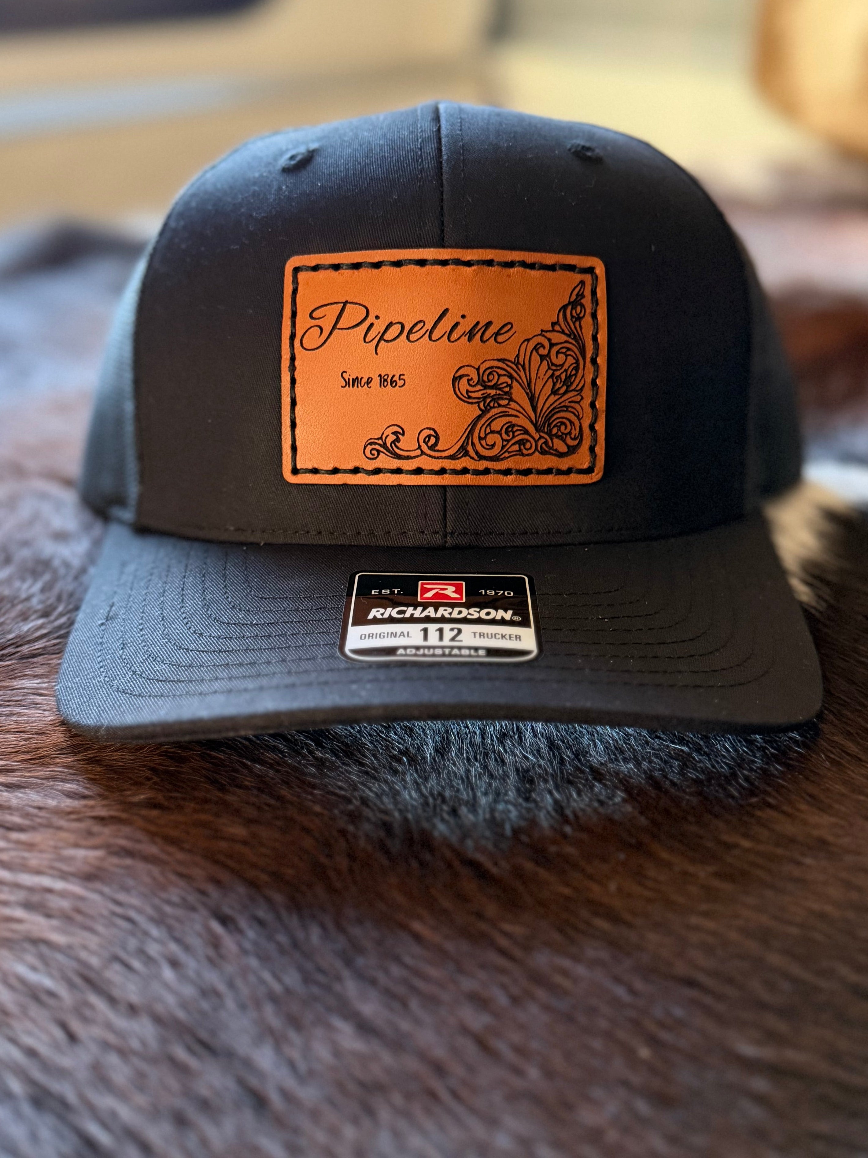 Black cap with brown leather patch and Richardson logo on a cowhide surface