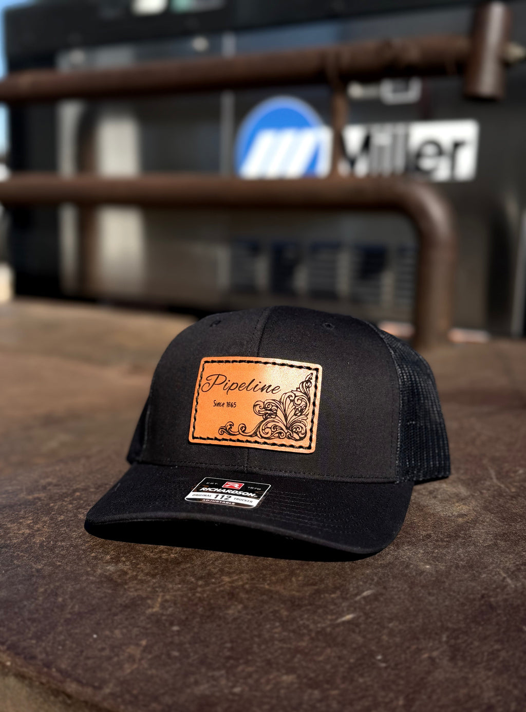 Black cap with a brown leather patch on a rustic surface