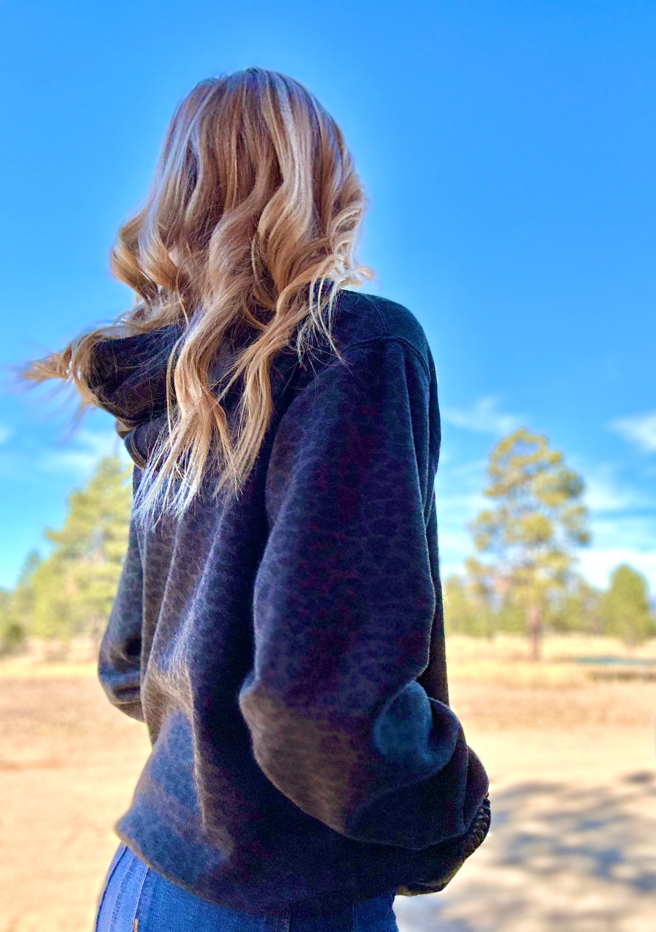 Person wearing a black leopard hoodie with a blurred natural background