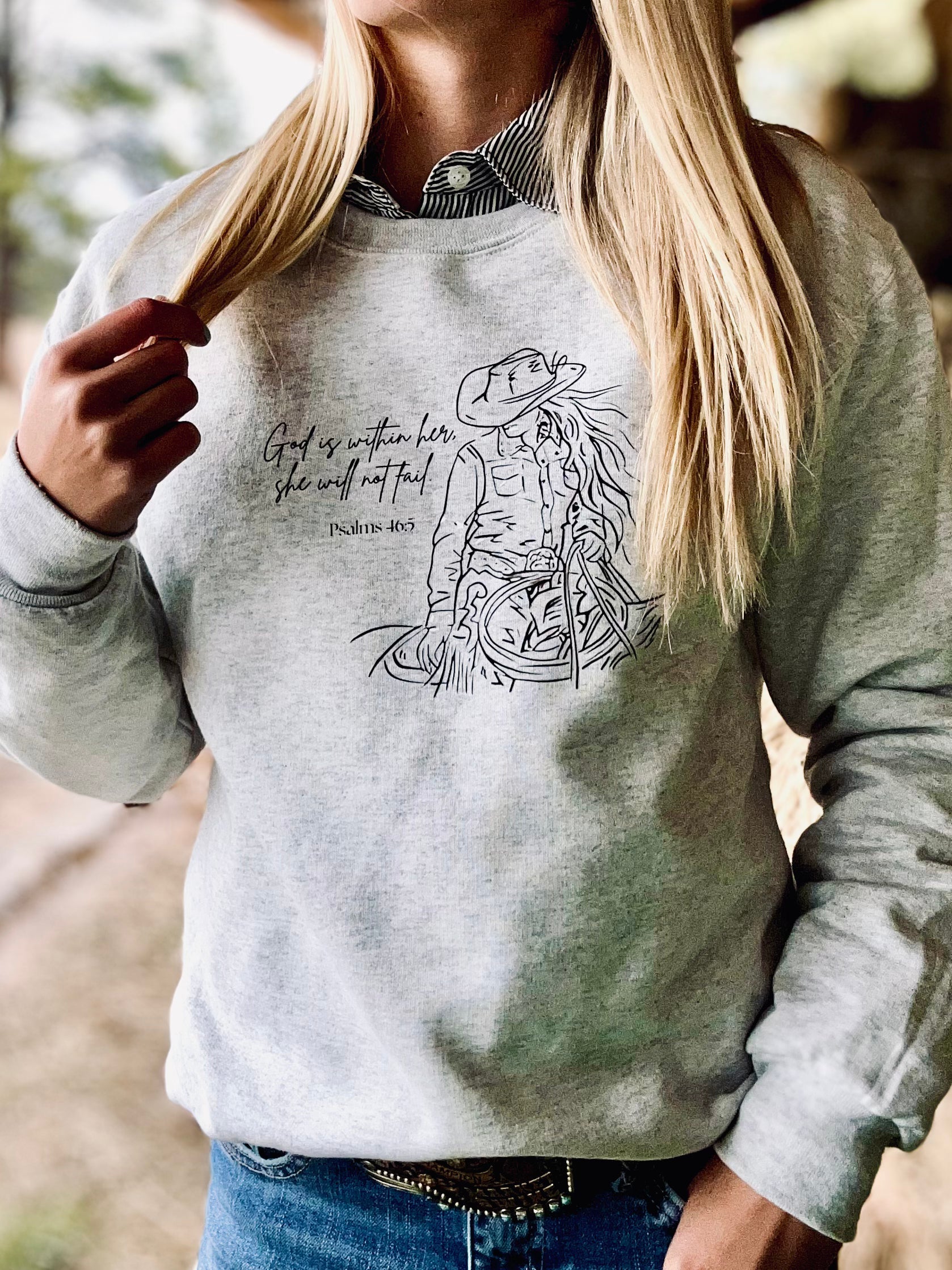 Person wearing a gray sweatshirt with a graphic design and text outdoors.
