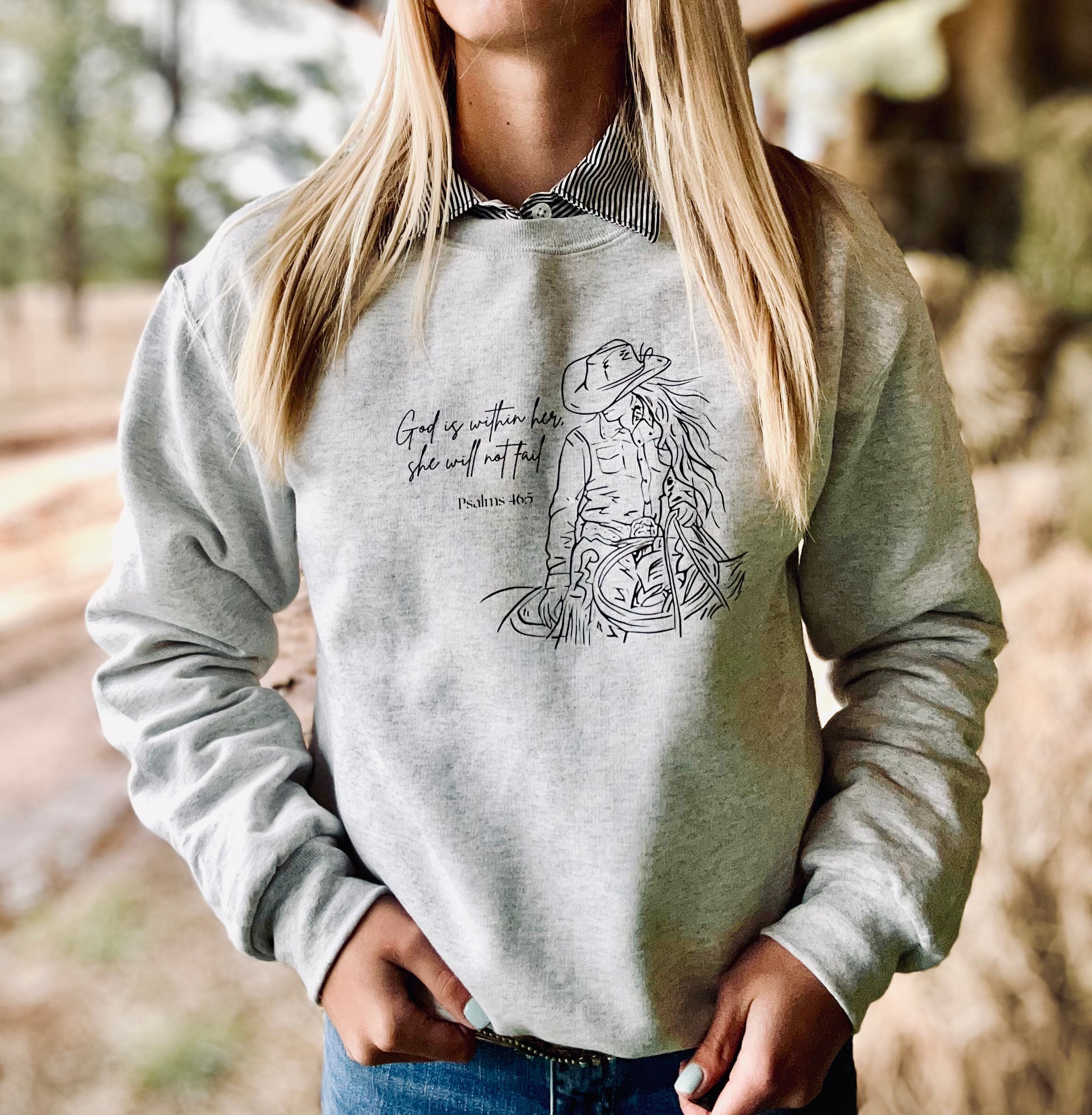 Person wearing a gray sweatshirt with a graphic design and text outdoors.