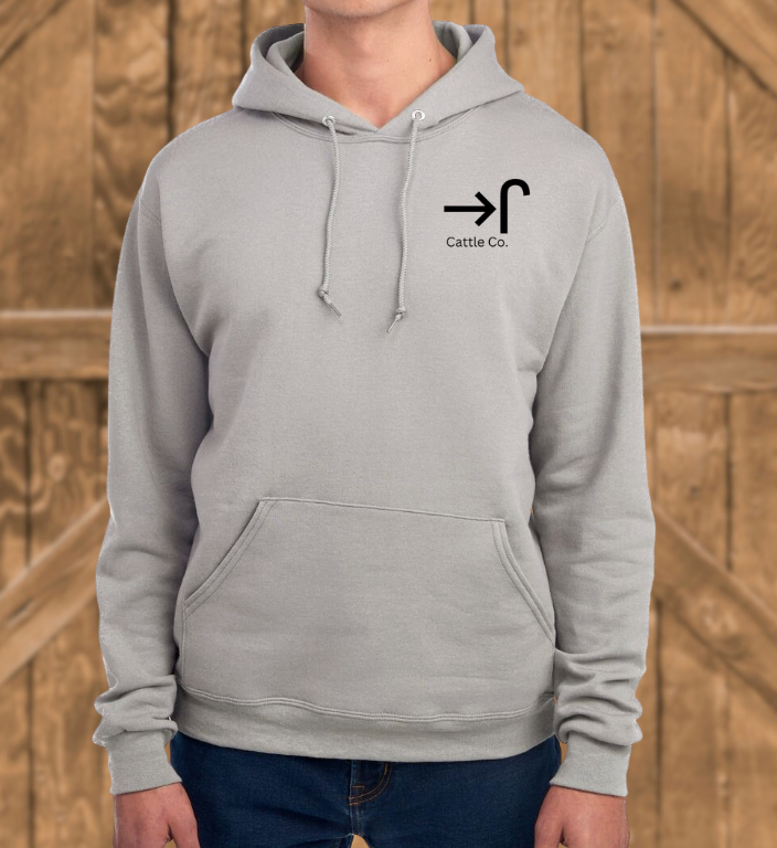 Person wearing a gray hoodie with a logo and text against a wooden background