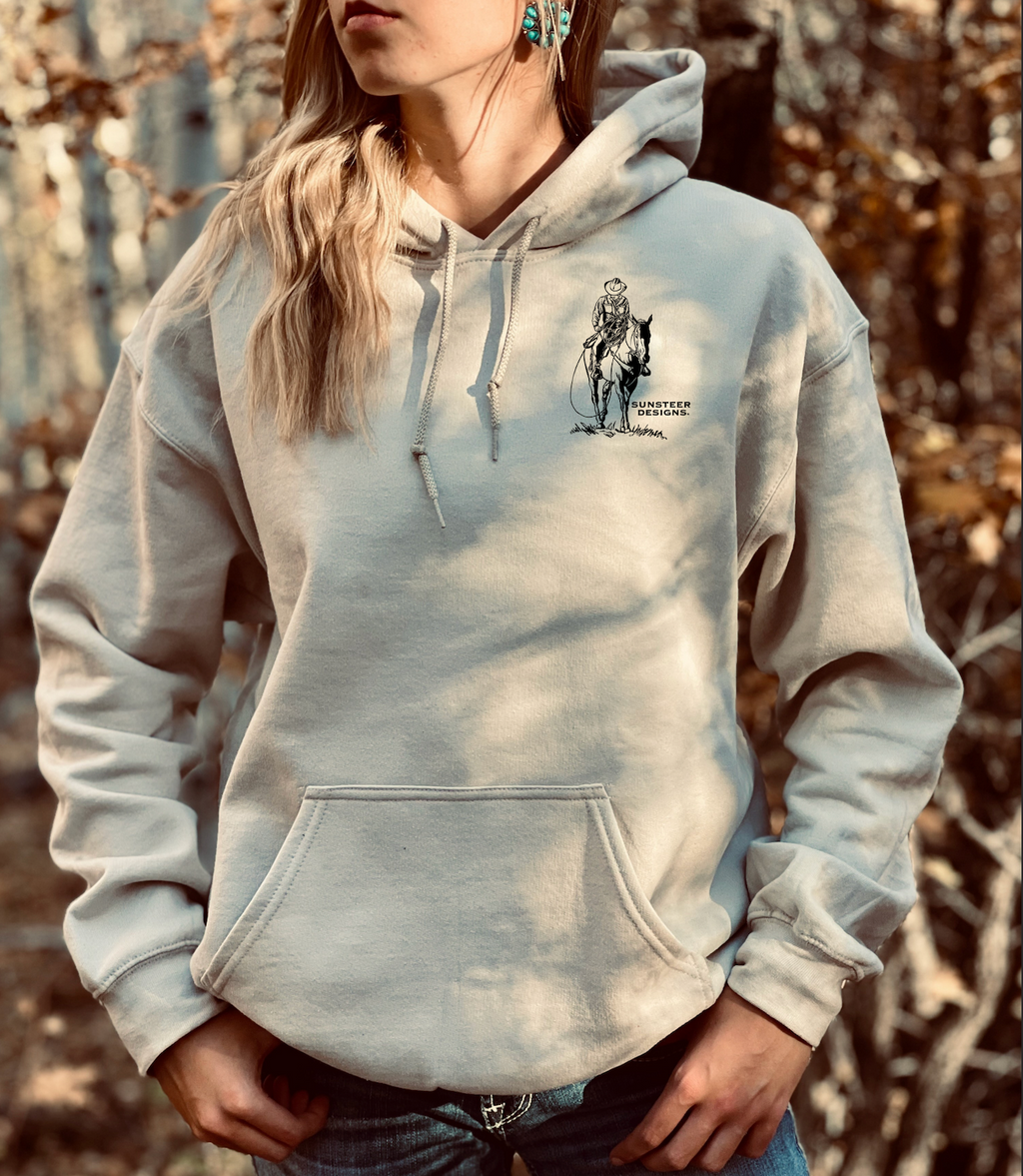 Person wearing tan hoodie with a logo in an outdoor setting