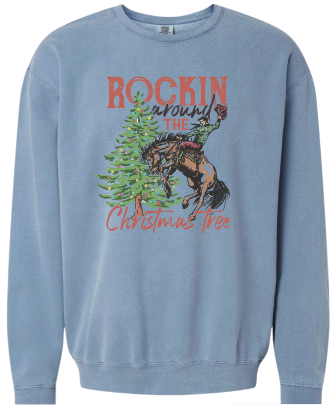 Blue sweatshirt with a graphic of a person on a horse and Christmas tree, text 'Rockin' around the Christmas tree'.