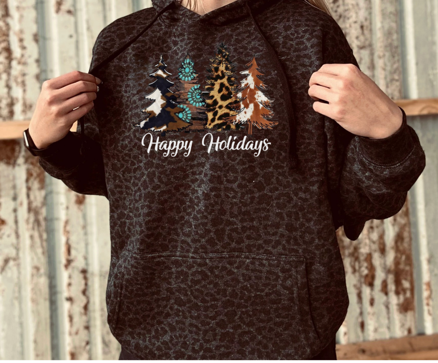 Person wearing a black leopard print hoodie with Christmas tree design and 'Happy Holidays' white text.