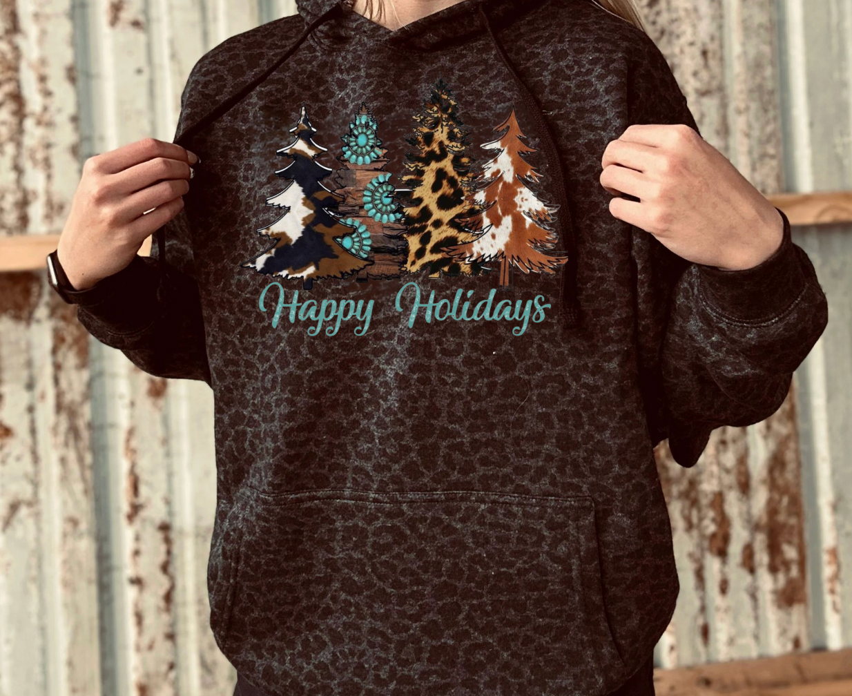 Person wearing a black leopard print hoodie with Christmas tree design and 'Happy Holidays' turquoise text.