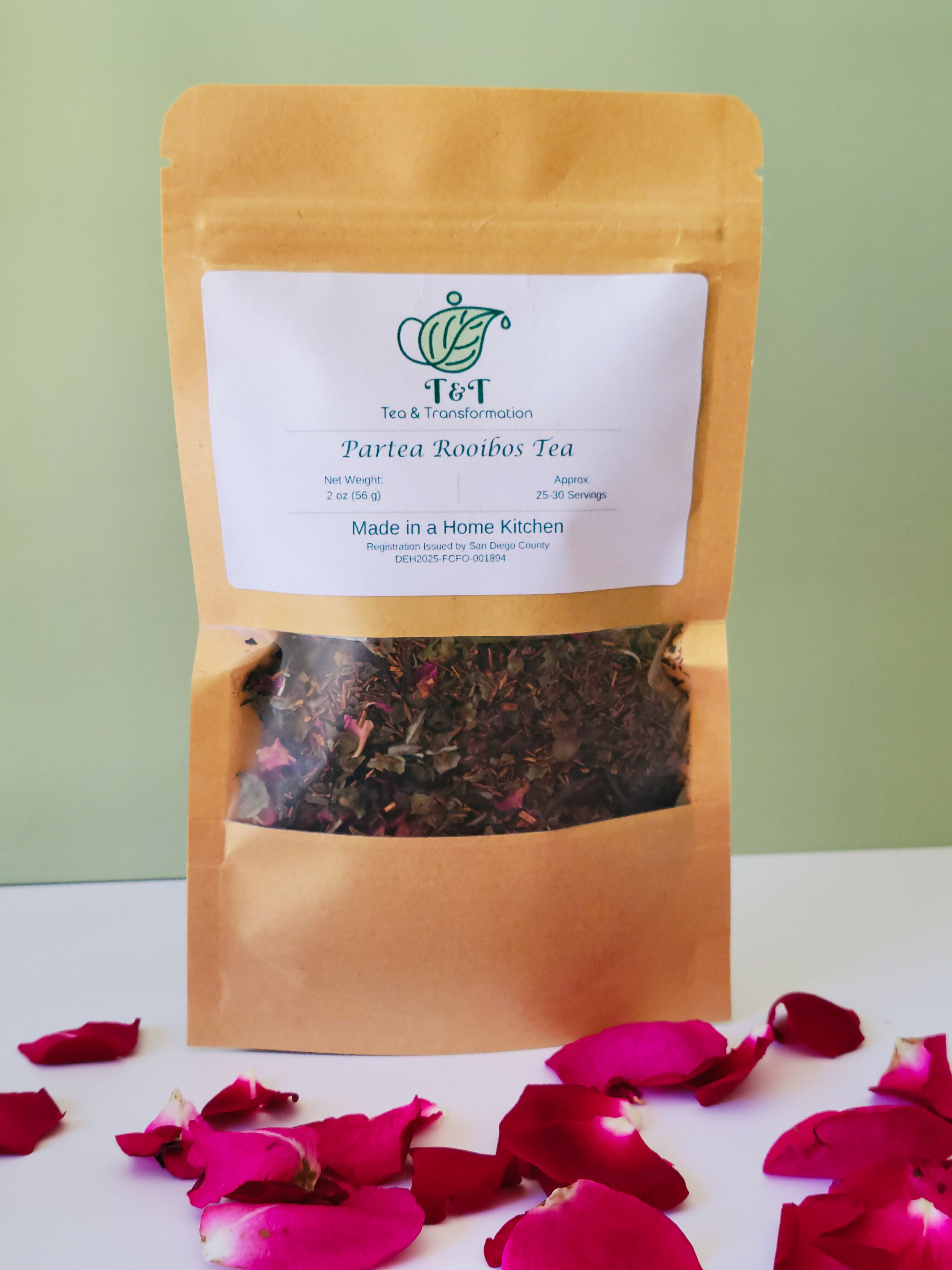 Partea Rooibos Tea in tea bag with white & green background & flower petals in foreground