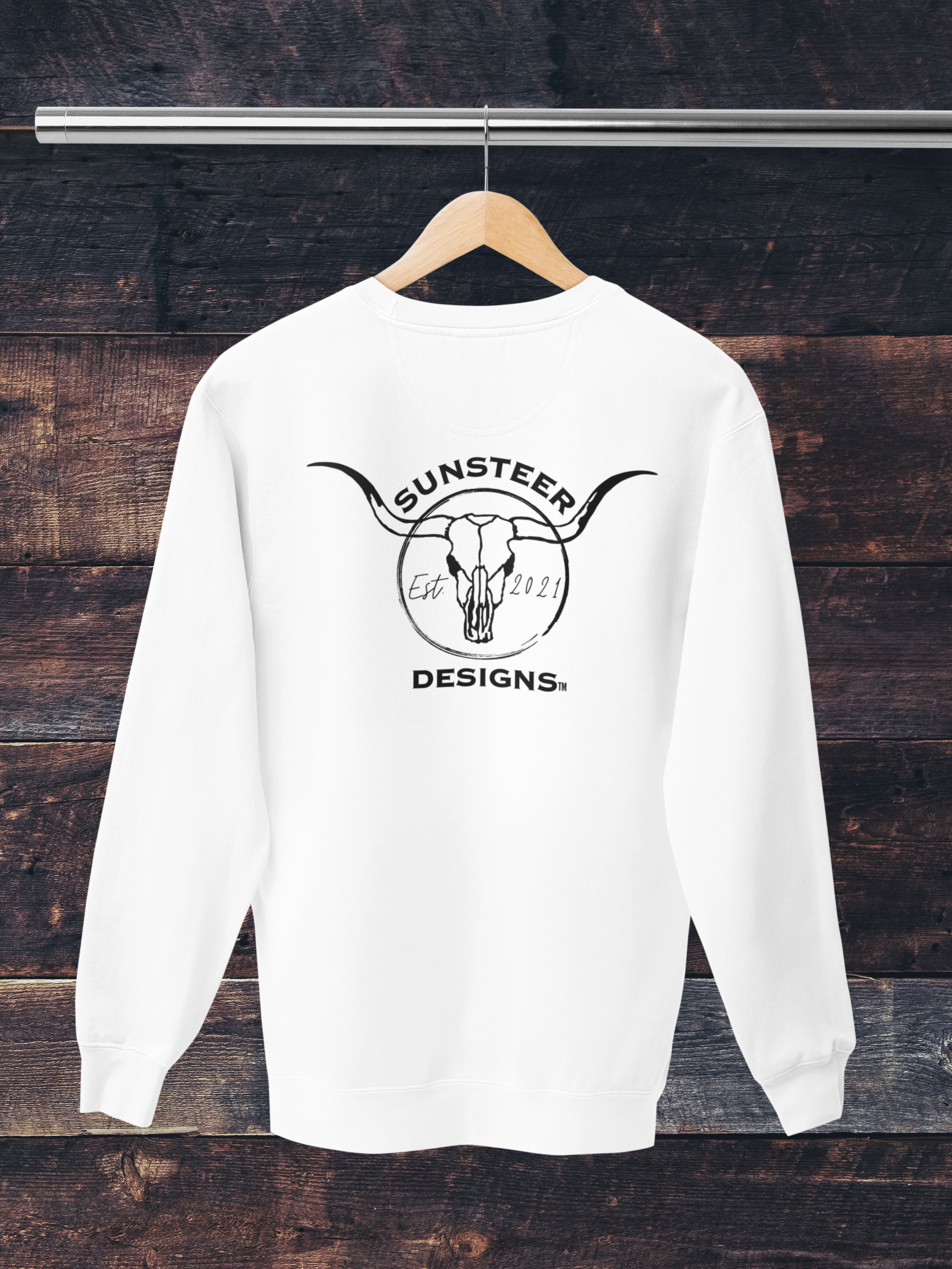 White sweatshirt with 'Sunsteer Designs' logo on a wooden background