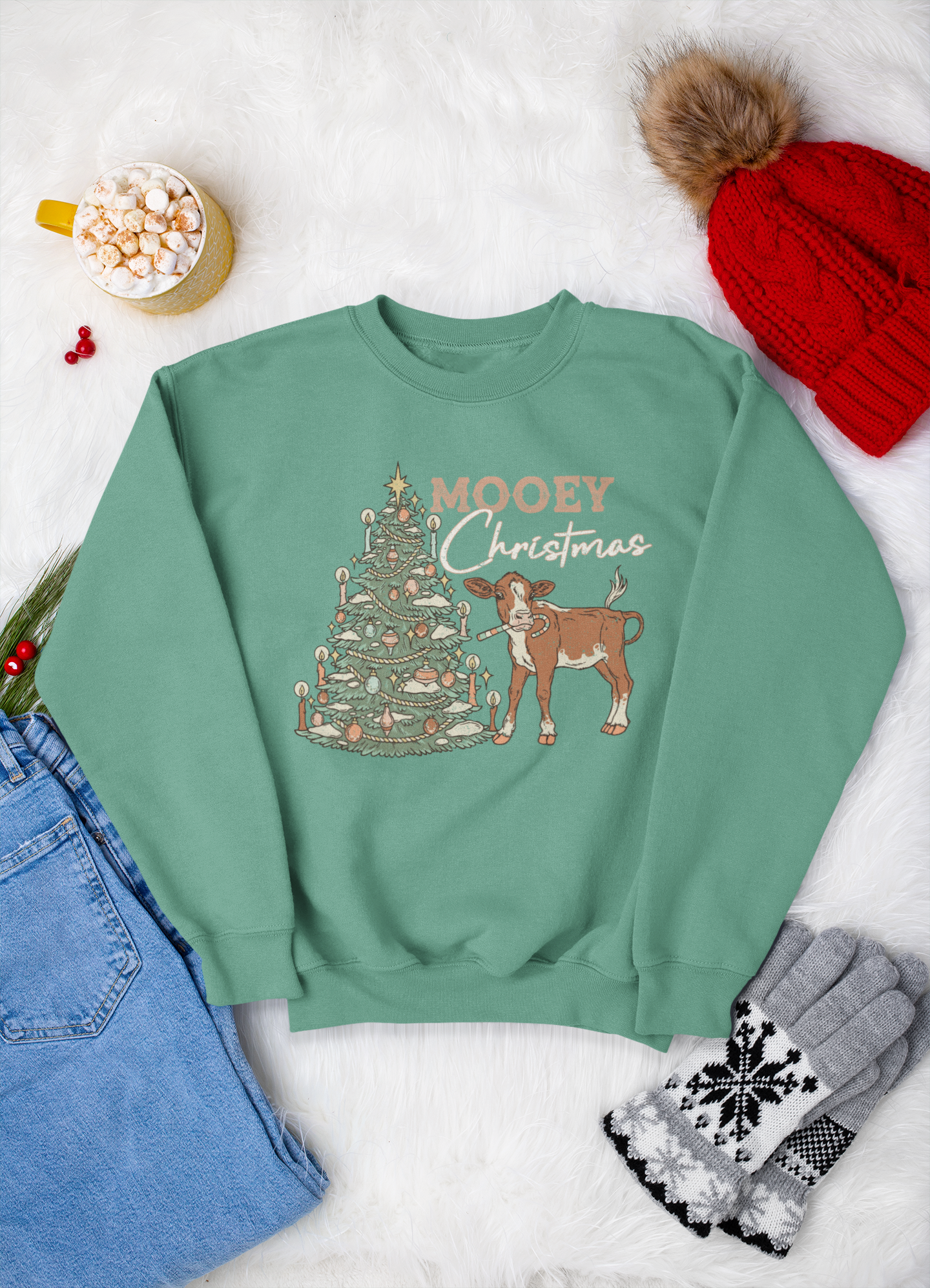 Green sweatshirt with Christmas design and text, surrounded by festive items on a white background