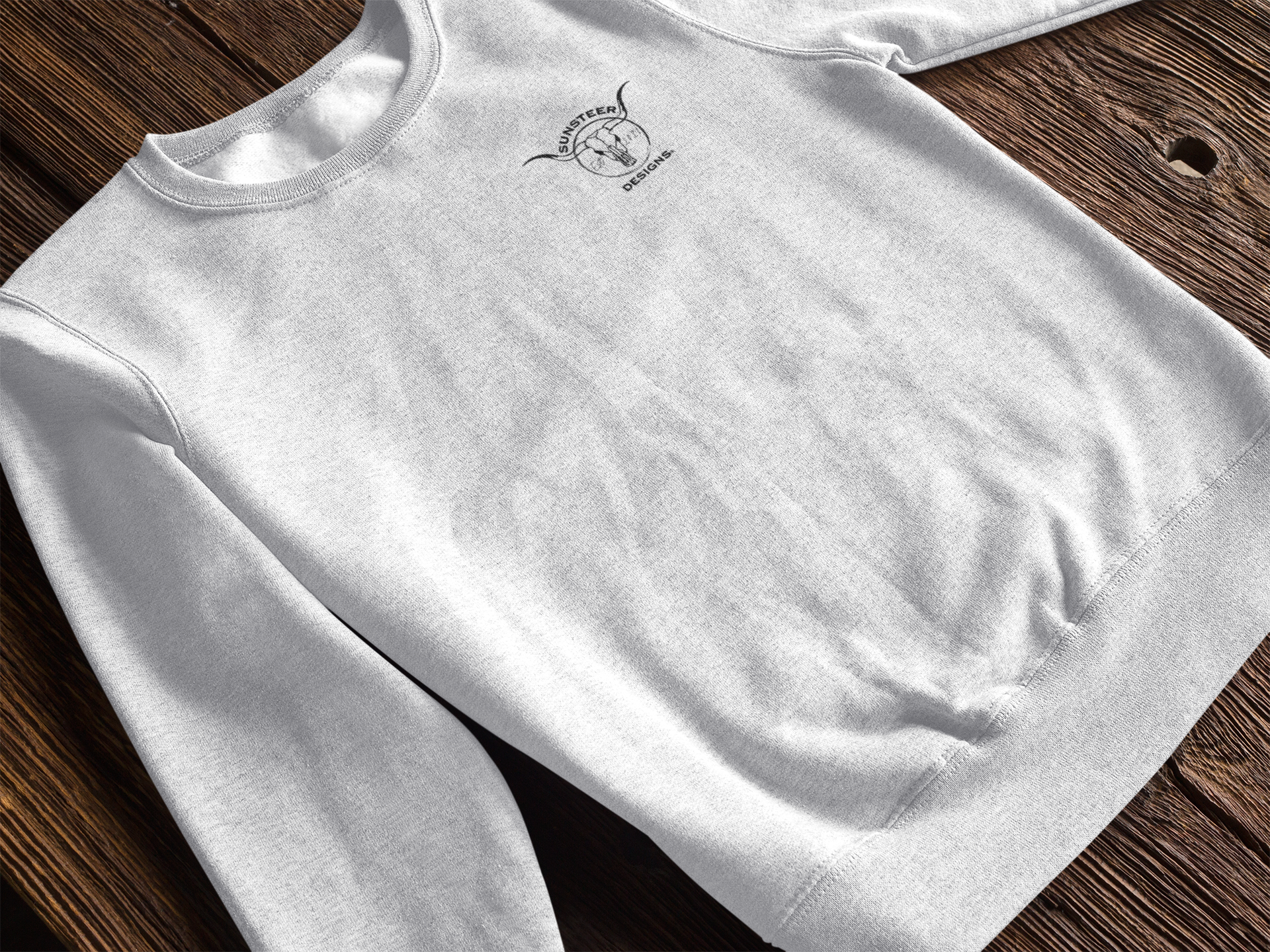 White sweatshirt with a logo on a wooden surface